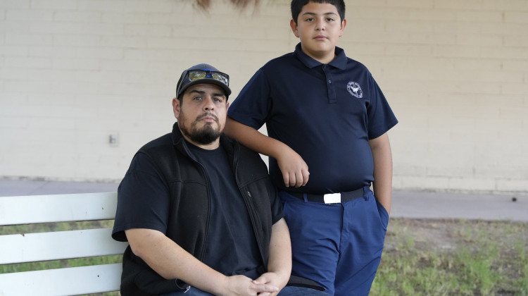 Aaron Galaz and his son pose for a photo on Wednesday, Oct. 18, 2023 in Phoenix. Aaron Galaz said his son is enrolled in a program that uses taxpayer funds to pay for private-school tuition in part so his son could be challenged more in class. At least four states that have made most children eligible for taxpayer-funded scholarships to private schools are seeing more families using the programs than planned. That could cost taxpayers, but it's early to know the exact budget implications. - AP Photo/Rick Scuteri