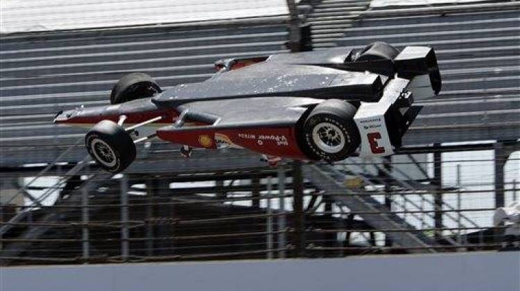 The car driven by Helio Castroneves, of Brazil, is airborne after hitting the wall in the first turn during practice for the Indianapolis 500 auto race at Indianapolis Motor Speedway in Indianapolis, Wednesday, May 13, 2015. - The Associated Press
