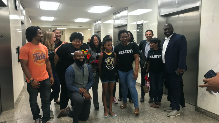 Believe High School Principal, Kimberly Neal, with flowers, and supporters celebrate after approval of their charter at the City-County Building Thursday, June 27, 2019. - Emily Cox/WFYI News