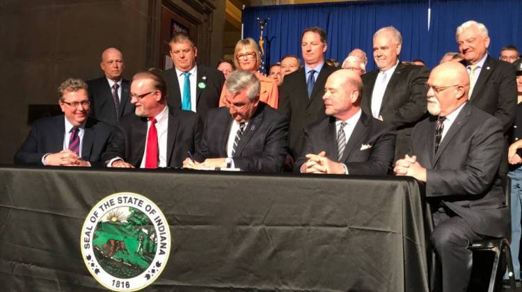 Governor Eric Holcomb, surrounding by lawmakers, signs into law a new $32 billion, two-year state budget. - Brandon Smith/IPB