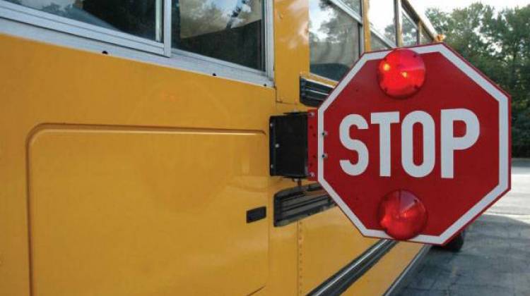 A stopped school bus displays an extended stop sign with flashing red lights, meant to halt motorists.  - U.S. Army/public domain