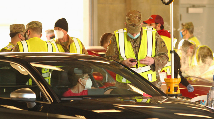 A member of the Indiana National Guard greets a patient during the mass COVID-19 vaccination clinic at the Indianapolis Motor Speedway on Friday, March 5.  - Doug Jaggers/WFYI