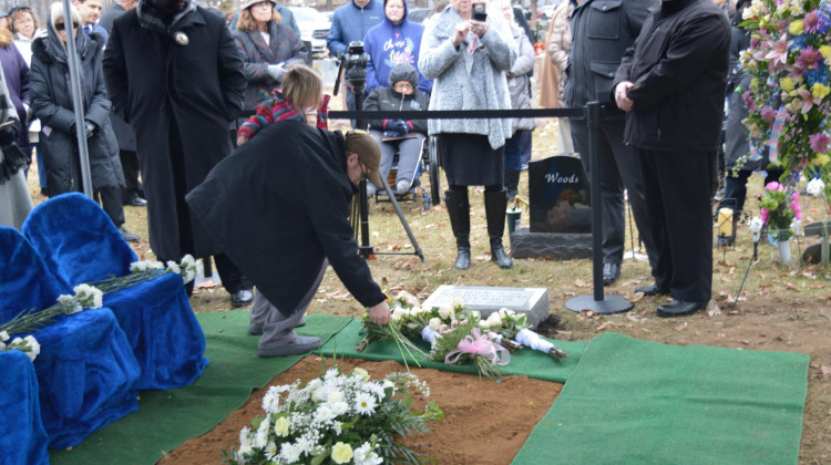 A man and child lay flowers on the headstone for the 2,411 fetal remains that were found in Dr. Ulrich Klopfer's garage in September 2019. The burial service was at Southlawn Cemetery in South Bend on Wednesday, Feb. 12, 2020. - Jennifer Weingart/WVPE