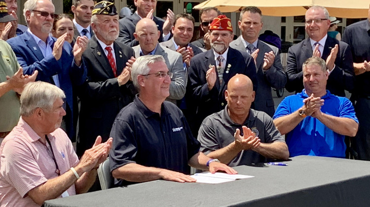 Gov. Eric Holcomb, seated center, at a ceremonial bill signing for the military pension tax exemption.  - Brandon Smith/IPB News