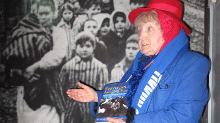 Eva Kor showing a picture of herself on the wall at the Auschwitz concentration camp. - Stan Jastrzebski/WBAA News