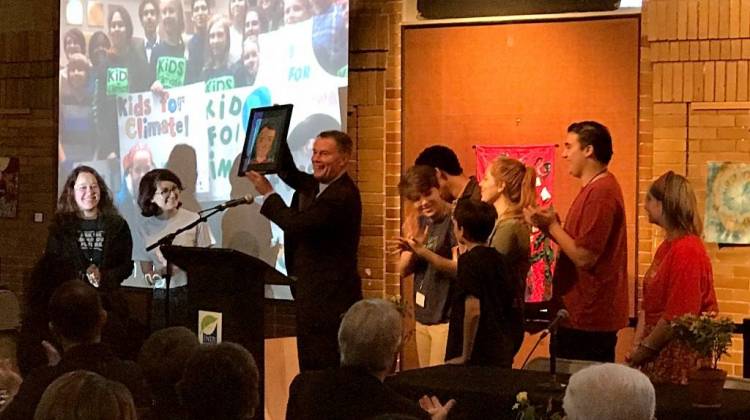 Indianapolis Mayor Joe Hogsett accepts a gift from Cora Gordon (clapping, right) and other members of Youth Power Indiana, which pushed for a city-county climate resolution earlier this year. - Nick Janzen/IPB News