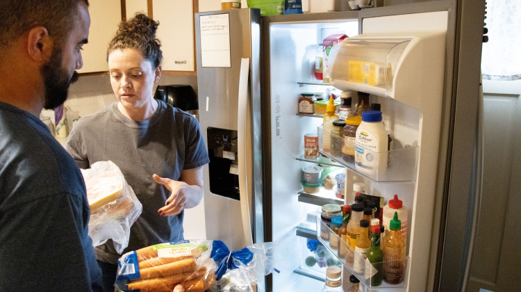 Josu 'Z' Barros and spouse Carrie Barros of Evansville,  stock the fridge after a shopping trip. A family of six with four teens/preteens, they can't afford to waste food. Carrie said she often under-shops for groceries to avoid waste. Experts think many families have poor inventory management skills, which  leads to food waste. - Tim Jagielo / WNIN News