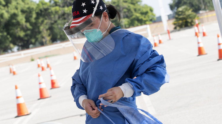 A health worker dons protective gear at a drive-through COVID-19 testing site set up by the Los Angeles Fire Department in Inglewood, Calif., on Monday. The Trump administration has released new guidelines on testing. - Valerie Macon/AFP via Getty Images