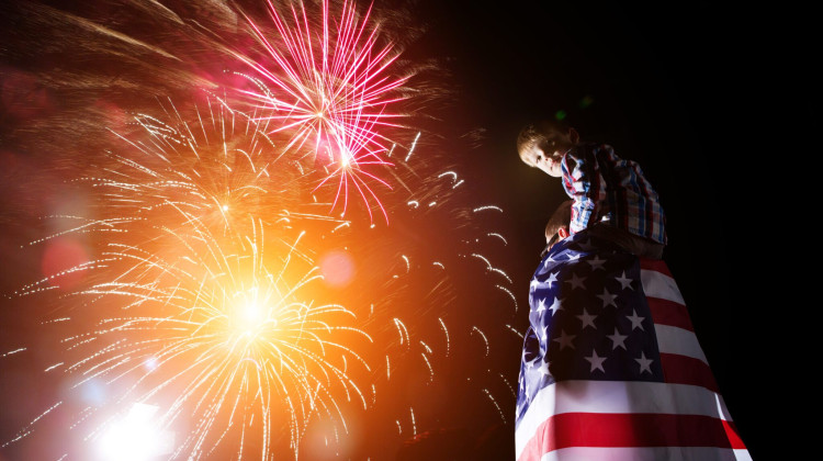 Family on Independence Day admires the fireworks with the American flag in their hands. 4th of July - Photo/Getty Images