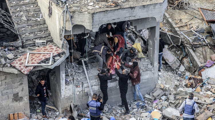 Men recover the body of a Palestinian killed in the aftermath of an overnight Israeli strike at al-Maghazi refugee camp in Gaza on Monday, as the war between Israel and Hamas carries on. - Mahmud Hams / AFP via Getty Images