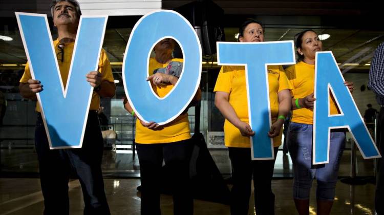 Attendees hold letters reading "vote" in Spanish during a campaign event with Tim Kaine.