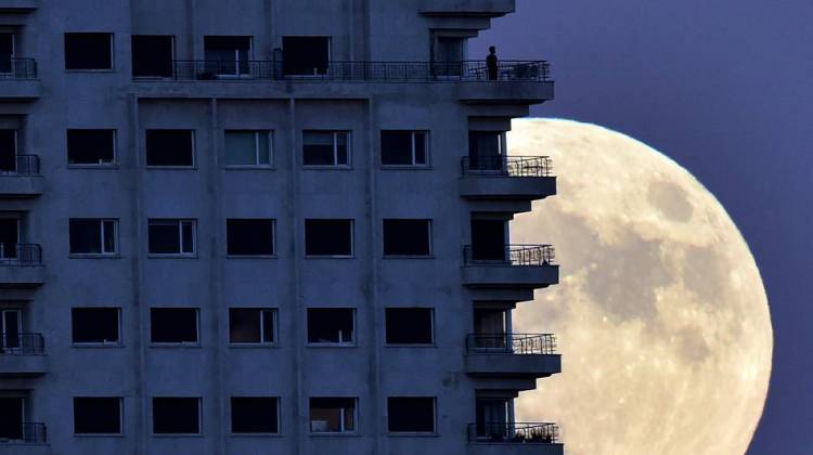 With the Nov. 13 supermoon rising in the background, a man looks out from a balcony in Madrid. At its closest pass to Earth, the full moon can look up to 14 percent bigger and 30 percent brighter, NASA says. - Gerard Julien/AFP/Getty Images