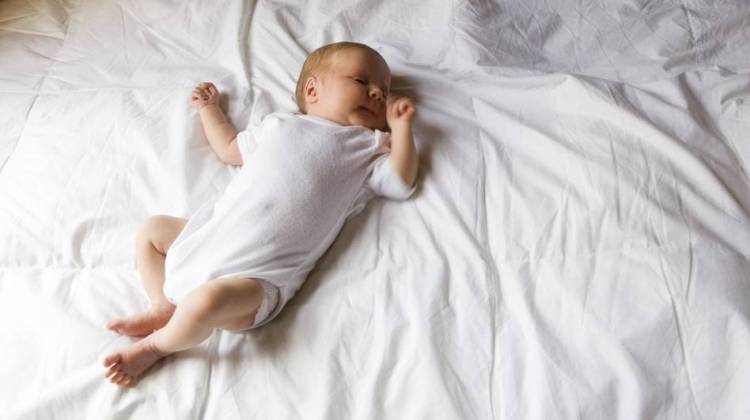 Newborn baby is shown sleeping on a bed. A new report says it's much safer for a baby to sleep alone on a crib with no pillows or blankets. - Purestock/Getty Images/Purestock