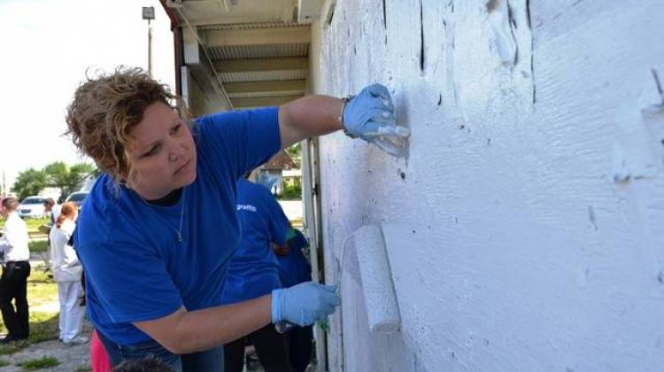 A volunteer paints over graffiti to kick off a graffiti abatement program Wednesday. - Ryan Delaney/WFYI
