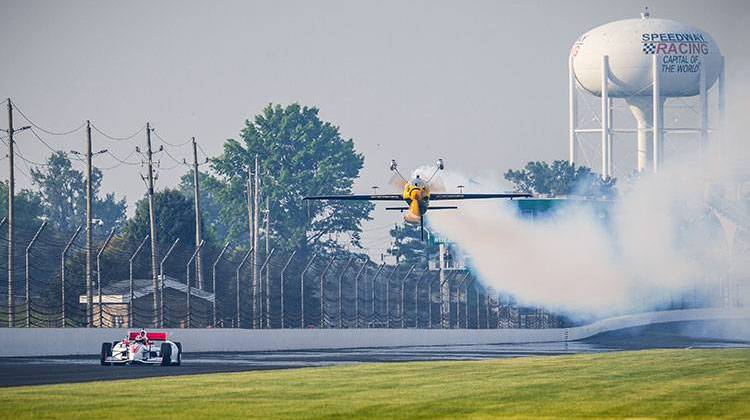 Indianapolis 500 Champion Alexander Rossi drives down the backstretch of the Indianapolis Motor Speedway as two-time Red Bull Air Race world champion KirbyChambliss flies above. - Courtesy Red Bull Media House