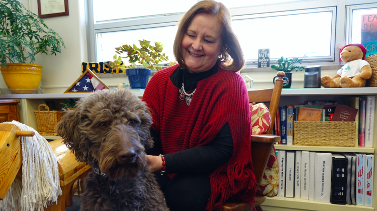 Rebecca Heger, Cathedral High School's mental health and addictions counselor, looks at 2-year-old Finn, a therapy dog at the school since 2015. - Eric Weddle/WFYI Public Media
