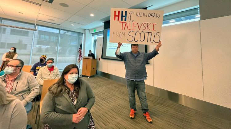 Michael Oles, national field director of advocacy organization Our Revolution, holds a sign at the Health and Hospital Corporation of Marion County's board of trustees meeting Tuesday, Oct. 18. - Farah Yousry/WFYI