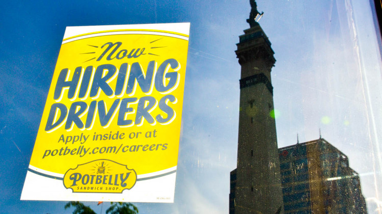 A hiring sign on the window of a sandwich shop with the reflection of the Indiana State Soldiers and Sailors Monument in the background.  - Justin Hicks/IPB News