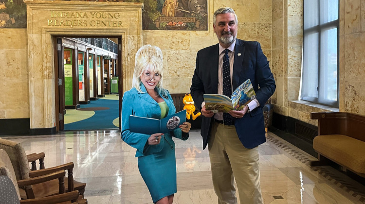 Gov. Eric Holcomb poses beside a cardboard cutout of Dolly Parton at an event celebrating the statewide expansion of the singer and philanthropist's Imagination Library program on Thursday, Aug. 24, 2023.  - Violet Comber-Wilen/IPB News