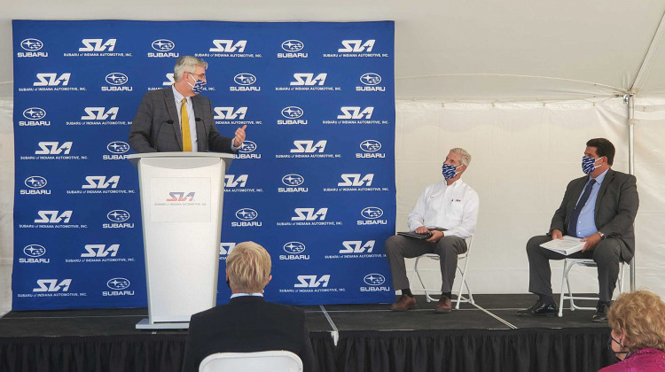 (Left to right) Gov. Eric Holcomb speaks at Subaru of Indiana Automotive ground breaking with SIA Vice President Scott Brand and Lafayette Mayor Tony Roswarski sitting on stage. - Samantha Horton/IPB News