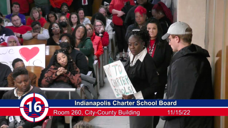 A woman holds a sign that reads "'No' to charter schools!" during a meeting of the Indianapolis Charter School Board that lasted more than four hours on Tuesday, Nov. 15, 2022. The board voted on applications to replicate two charter high schools in Pike Township. - Government Access Channel 16 / Screen capture