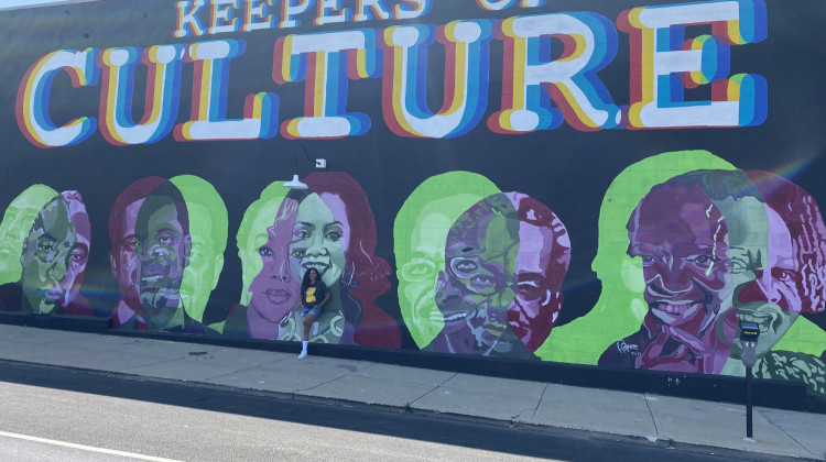 Muralist and Painter Ashley Nora stands with the mural she created for the first BUTTER Fine Arts Fair in 2021. (WFYI News/Abriana Herron) - WFYI News/Abriana Herron