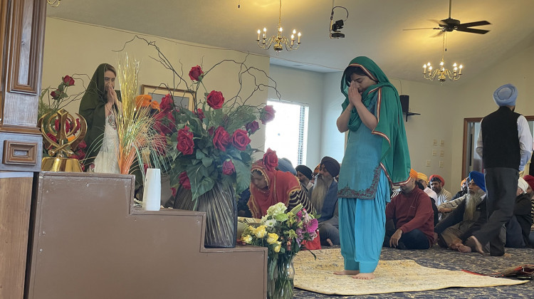 As people filed into the room, it’s tradition to bow towards the holy book, which is placed on an elevated surface and covered by a canopy. People also place money or other gifts at the front of the takhat. - (Carter Barrett/WFYI)