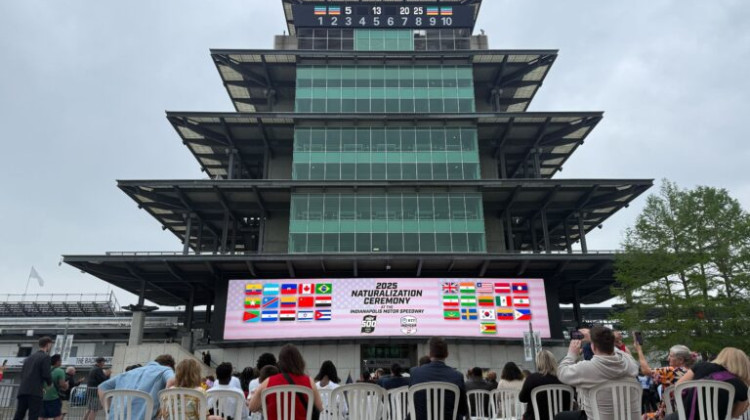 The Indianapolis Motor Speedway hosts a judicial naturalization for the fourth straight year on Tuesday, May 13, 2025. New citizens, pictured in white chairs, received welcome materials complete with little jugs of milk in a nod to the Indianapolis 500 race tradition. - Casey Smith / Indiana Capital Chronicle