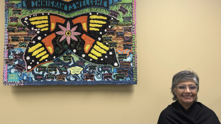 Immigrant Welcome Center CEO Gurinder Kaur stands near a mural at the center. - Samantha Horton / WFYI