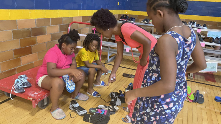 Kewanna Heard, a mother of seven, helps her children pick out shoes while at a back-to-school event in Indianapolis offering free school clothes and supplies. - Elizabeth Gabriel/WFYI News