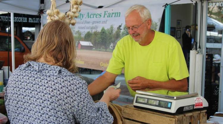 Montgomery County-based grower Gary Cox makes change for a customer in his Trinity Acres Farm tent at the Lafayette Farmers Market. - Annie Ropeik/IPB News