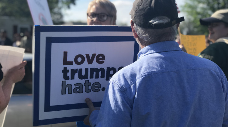 A protester at President's Trump campaign rally holds a sign across the street from the president's supporters. - Barbara Anguiano/WVPE