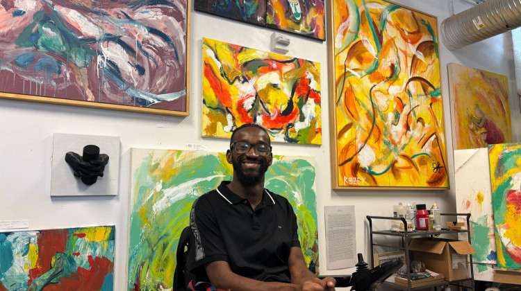 Dozens of vibrant colored paintings line the walls of artist Johnson Simon’s studio at the Harrison Center in downtown Indianapolis. Simon is a recent recipient of the 2025 Midwest Award for Artists with Disabilities. - Abriana Herron / WFYI