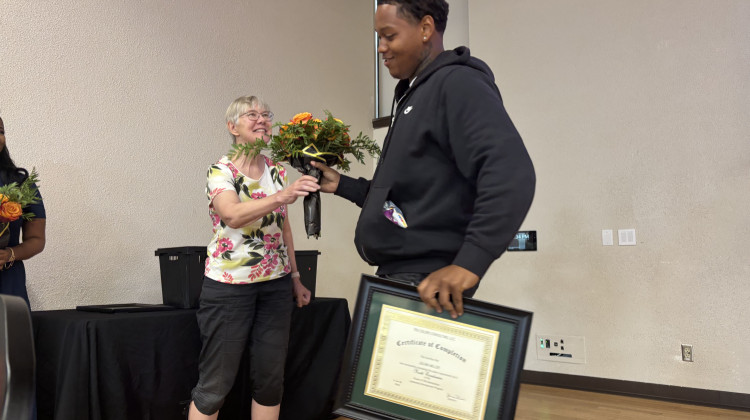 Julian Miller, 18, accepts flowers from audience member at the Power of TRU Generations conference, Sept. 20, 2025. It is an event focused on highlighting issues of youth violence and mental health in Indianapolis, hosted by 11 Black young men. - Abriana Herron / WFYI