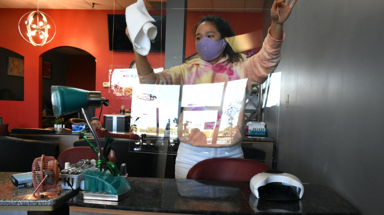 A younger worker at a nail salon cleans a plexiglass shield being used to prevent the spread of COVID-19.  - Justin Hicks/IPB News