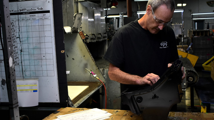 A worker at Decatur Plastic Products performs a final inspection on a piece that has just come off the assembly line. DPP specializes in molded plastic parts that are used in car dashboards and consoles.  - Justin Hicks/IPB News