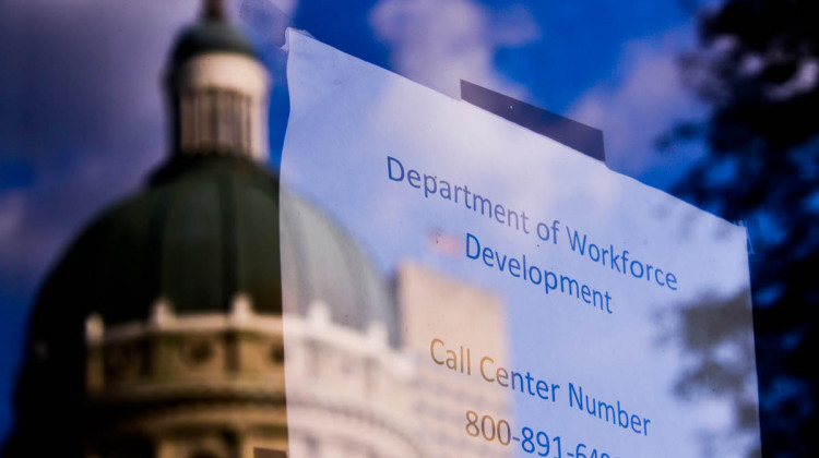 The Indiana Statehouse reflected in a window giving contact information related to unemployment benefits. - Justin Hicks/IPB News