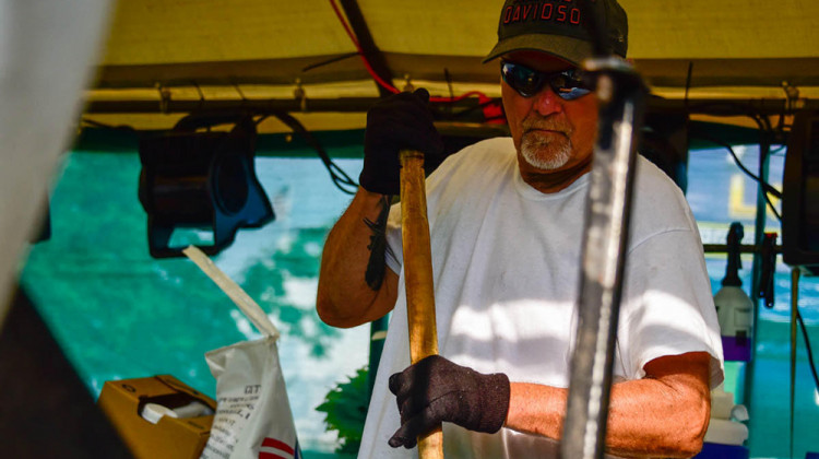 Bill Rairigh, a professional kettle corn concessionaire, stirs kernels in a large burner under a tent at the Indiana State Fair.  - Justin Hicks/IPB News