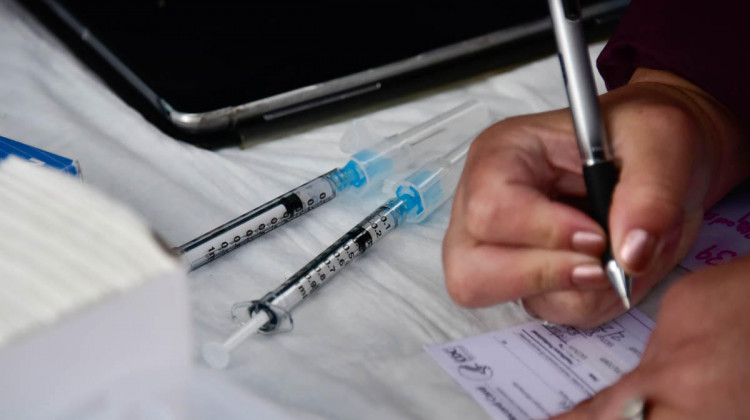 A worker at a COVID-19 vaccination clinic fills out paperwork.  - (Justin Hicks/IPB News)