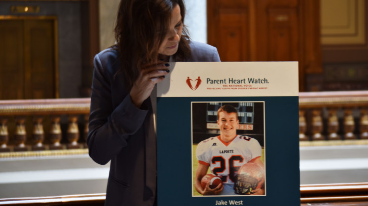 Julie West holds a poster of her son, Jake, inside the Indiana Statehouse on Wednesday, March 22, 2023. Jake died from an undetected heart condition, and collapsed while playing football at his La Porte High School.   - Elizabeth Gabriel/WFYI