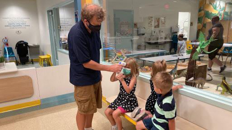 Jeremy Sander helps his daughter, Jordan, 5, take her temperature with an infrared thermometer at Lodgic Kids Camp in Champaign, Ill. - Lee V. Gaines/Side Effects Public Media