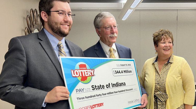 Hoosier Lottery Commission Chair William Zielke and Hoosier Lottery Executive Director Sarah Taylor (center and right) present a ceremonial check to John Roeder (left) with the governor's office on Aug. 16, 2022. The check represents the surplus revenue for the state generated by the Hoosier Lottery. - Brandon Smith/IPB News