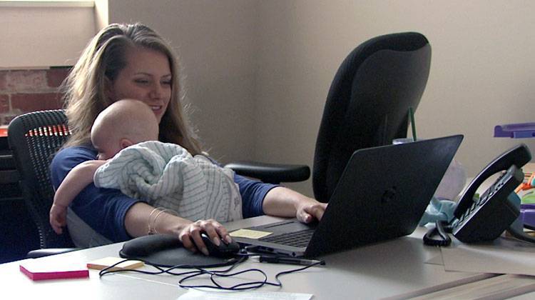 Whitney Pflanzer, senior account executive at Borshoff, works while her son Roman naps in her arms. - Steve Burns/WTIU