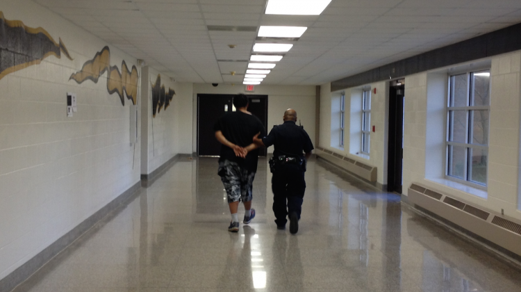 Indianapolis Public School Police Sgt. Floyd Peterson walks a teenager down the hallway at Arlington High School on Wednesday March 8, 2016. Seven juveniles were arrested and more were initally detained by IPS police aftter a fight between two students that also involved individuals from outside the building. - Eric Weddle / WFYI Public Media