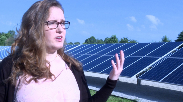 Indiana University student Savannah Rodrigue stands in front of a solar array next to a water booster station in Bloomington which helps to offset some of the station's energy use. - Rebecca Thiele/IPB News