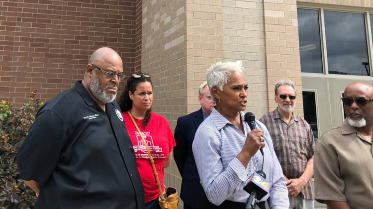 Sabae Martin, of the Butler Tarkington Neighborhood Association Board, holding microphone, stands outside School 43 on Tuesday, July 16, 2019, to discuss concerns about the school. - Eric Weddle/WFYI News