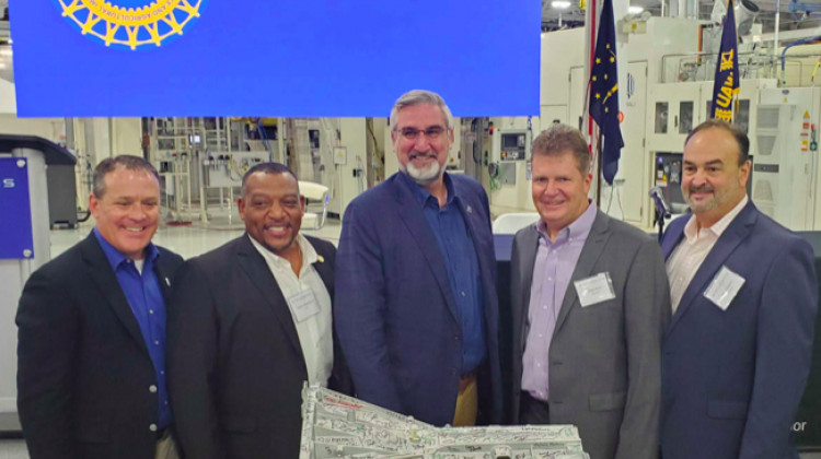 Kokomo Mayor Tyler Moore, UAW Region 2B director Wayne Blanchard, Gov. Eric Holcomb, Stellantis powertrain operations head Brad Clark and director of operations David Dukes sign the 5 millionth eight-speed transmission built at the plant.  - (Samantha Horton/IPB News)