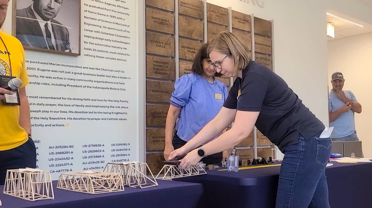 Pattie Mathieu, assistant professor of biomedical engineering at Marian University, places weights on students' bridges during the bridge competition. - Kirsten Adair / IPB News