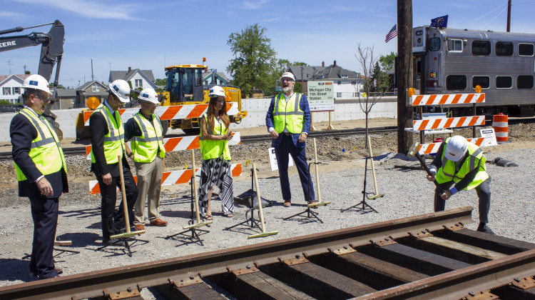 U.S. Sen. Todd Young hammers in a golden spike as part of the groundbreaking ceremony while officials, including Gov. Eric Holcomb, look on. - Jakob Lazzaro / WVPE