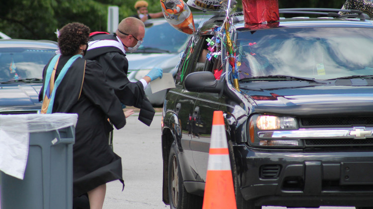 One of Manuel High School's teachers runs up excitedly to a vehicle during the school's drive-thru graduation.  - Lauren Chapman/IPB News